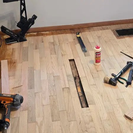 Hardwood flooring repair in progress with replacement boards installed