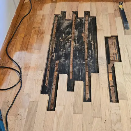 Hardwood flooring repair in progress after damaged boards were removed